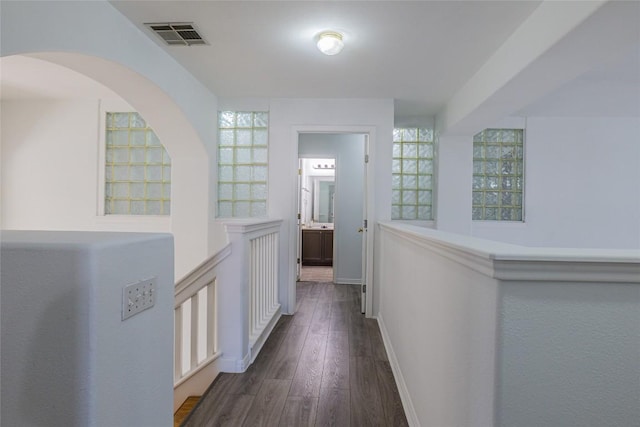 hall featuring visible vents, dark wood-type flooring, and baseboards