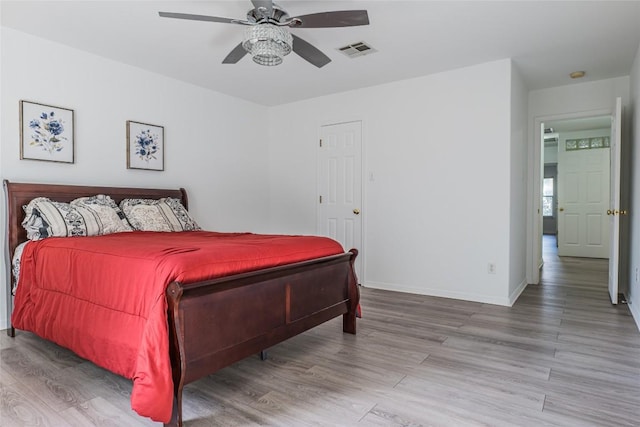 bedroom with ceiling fan, wood finished floors, visible vents, and baseboards