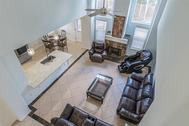 tiled living room featuring a sink, a healthy amount of sunlight, ceiling fan, and a fireplace