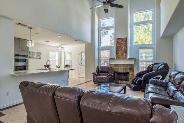 living room featuring a high ceiling, light tile patterned floors, visible vents, and a tile fireplace