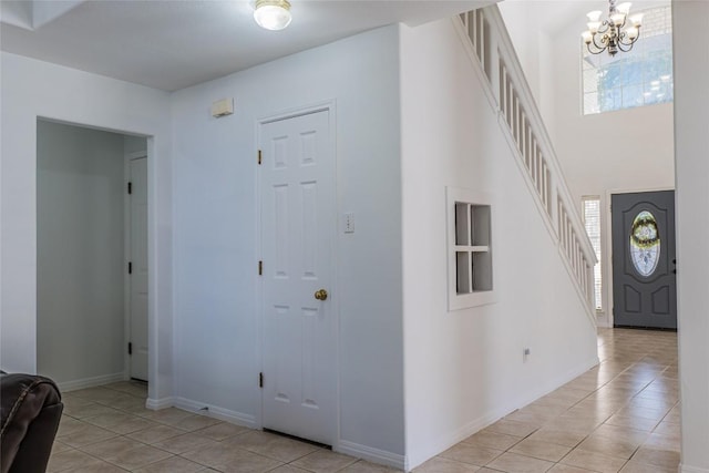 entrance foyer with stairs, plenty of natural light, light tile patterned floors, and a chandelier