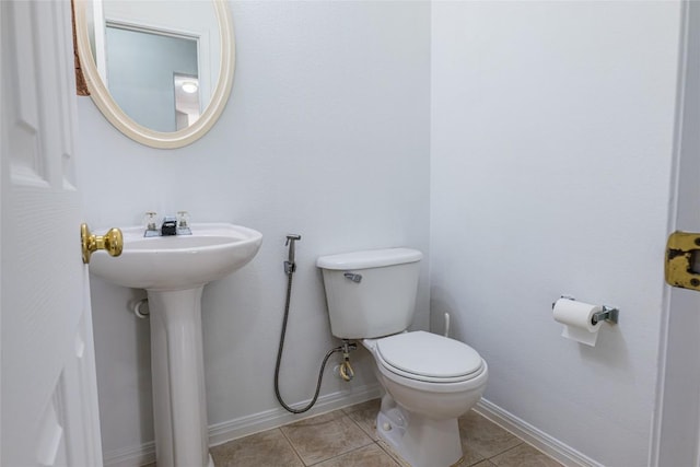 bathroom with a sink, baseboards, toilet, and tile patterned flooring