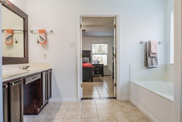 full bath featuring baseboards, double vanity, a sink, tile patterned flooring, and a garden tub