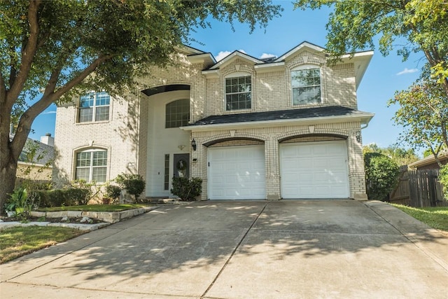 view of front facade with a garage, brick siding, driveway, and fence