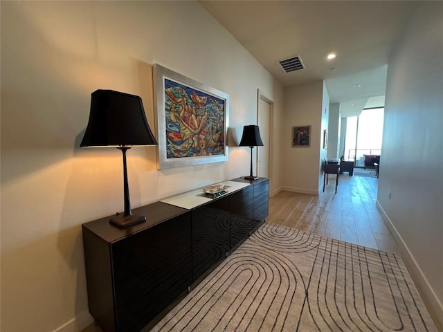 corridor with light wood-type flooring, visible vents, baseboards, and recessed lighting