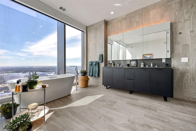 full bathroom with double vanity, visible vents, and a soaking tub