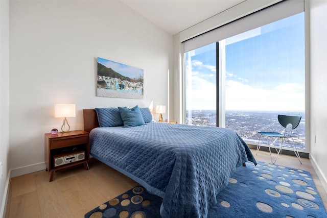 bedroom with vaulted ceiling, baseboards, and wood finished floors