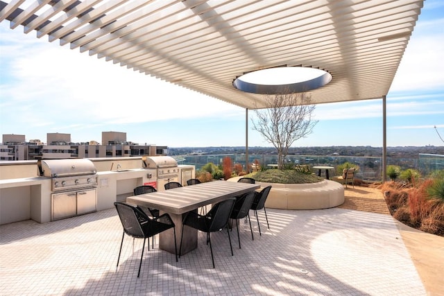 view of patio featuring grilling area, outdoor dining space, a city view, and exterior kitchen