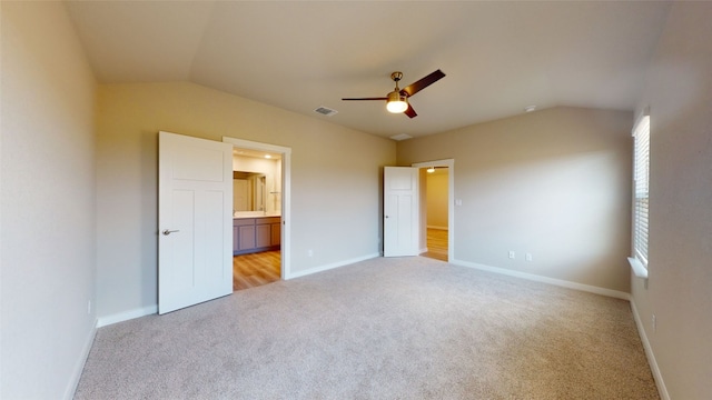 unfurnished bedroom with visible vents, lofted ceiling, light colored carpet, and baseboards