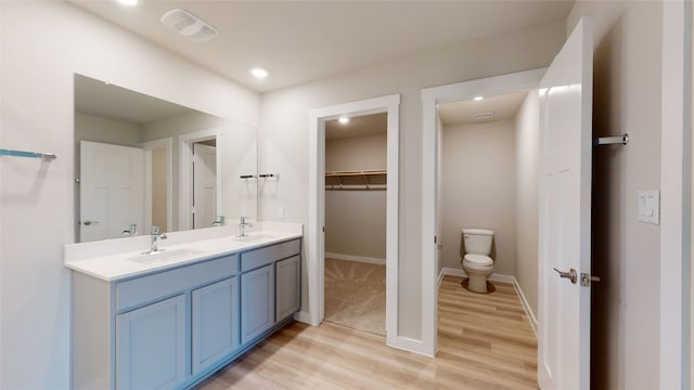 full bath featuring double vanity, wood finished floors, visible vents, and a sink