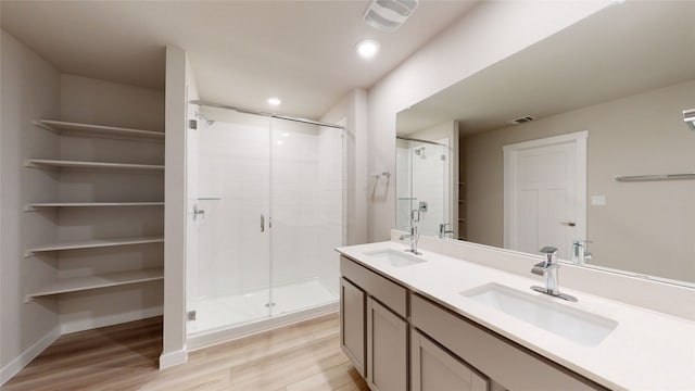 full bath with visible vents, a shower stall, wood finished floors, and a sink