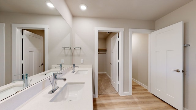 bathroom featuring double vanity, wood finished floors, and a sink