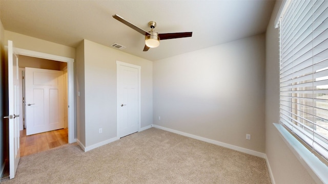 unfurnished bedroom with visible vents, light carpet, a ceiling fan, a closet, and baseboards