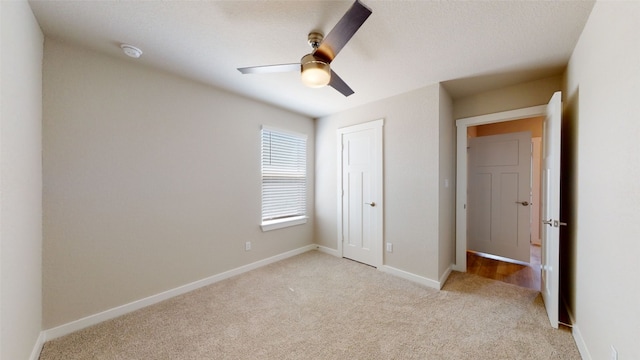 unfurnished bedroom featuring light colored carpet, baseboards, a closet, and ceiling fan