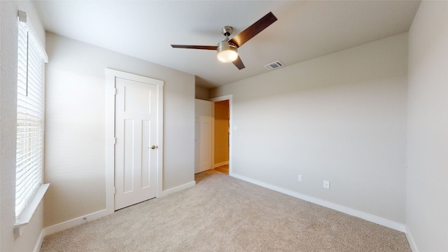 unfurnished bedroom featuring carpet flooring, multiple windows, baseboards, and visible vents