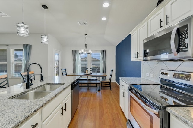 kitchen with light wood finished floors, visible vents, tasteful backsplash, appliances with stainless steel finishes, and a sink