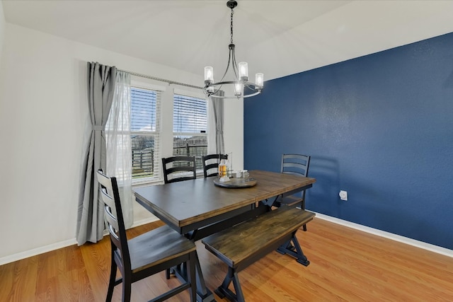 dining space with a notable chandelier, baseboards, and light wood-style floors