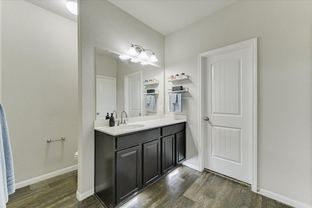 bathroom featuring toilet, vanity, baseboards, and wood finished floors