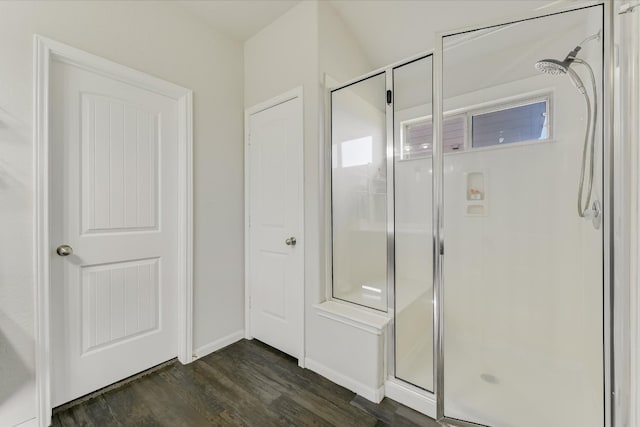 bathroom featuring a stall shower, baseboards, and wood finished floors