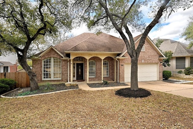 view of front facade featuring fence, a shingled roof, concrete driveway, a garage, and brick siding