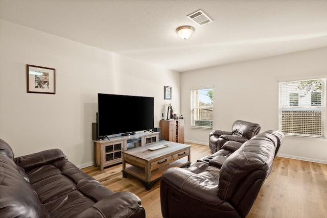 living room with baseboards, visible vents, and light wood finished floors