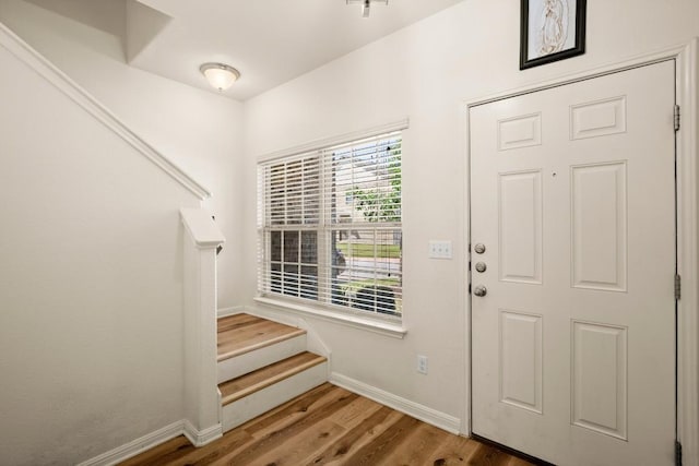 entrance foyer with stairway, wood finished floors, and baseboards