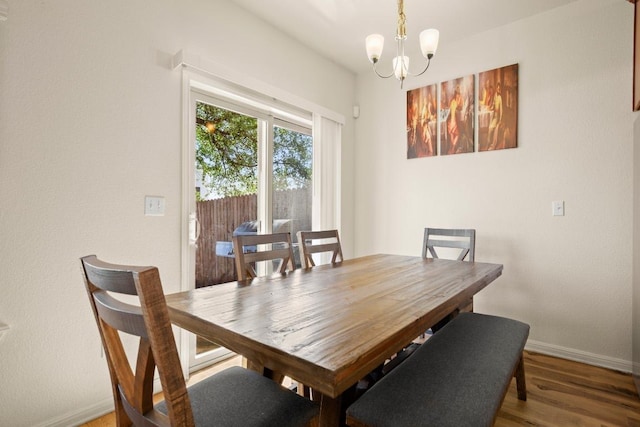 dining space featuring baseboards, an inviting chandelier, and wood finished floors