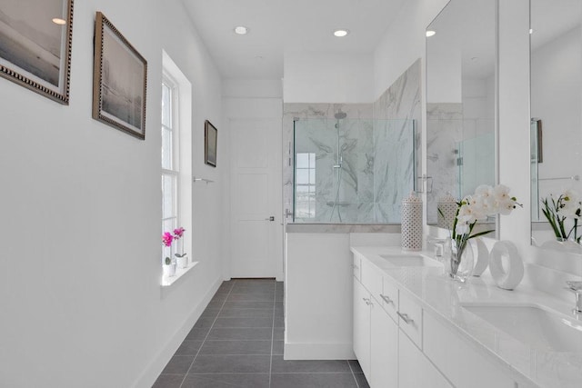 full bath with a sink, a marble finish shower, double vanity, and tile patterned flooring