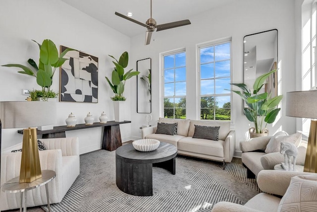 living area with a high ceiling, baseboards, and ceiling fan