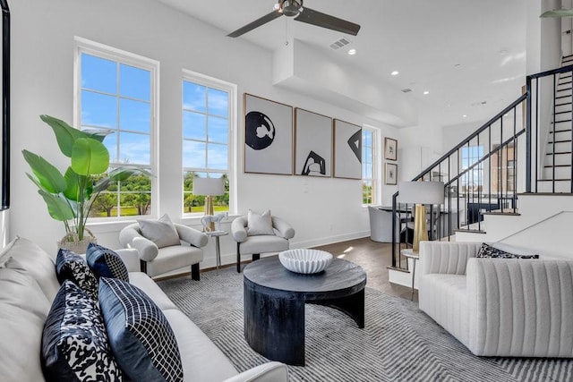 living room with a wealth of natural light, visible vents, wood finished floors, and stairway