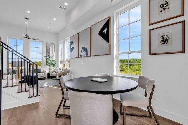 dining room with visible vents, baseboards, wood finished floors, and stairway