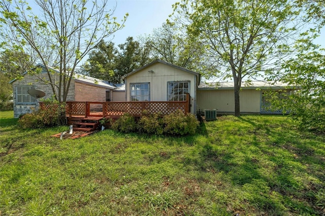 rear view of house featuring central air condition unit, a wooden deck, and a yard