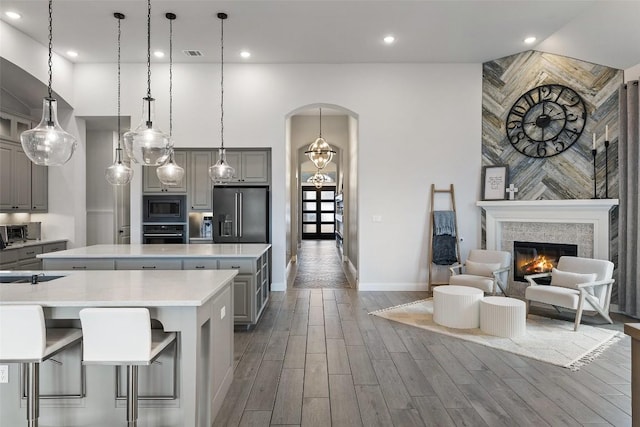 kitchen featuring visible vents, gray cabinets, a center island, stainless steel appliances, and arched walkways