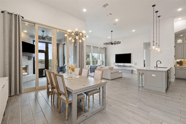 dining space featuring visible vents, recessed lighting, a fireplace, light wood-style floors, and a chandelier