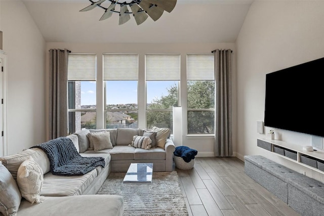 living room featuring baseboards, lofted ceiling, light wood-style floors, and a ceiling fan