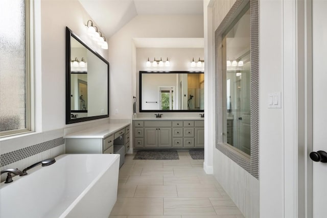 bathroom with a stall shower, vanity, lofted ceiling, and a freestanding tub