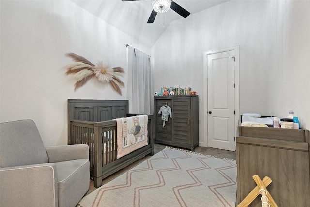 bedroom with ceiling fan, a nursery area, and vaulted ceiling