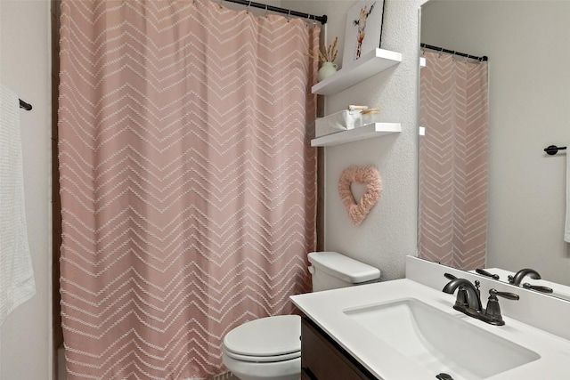 bathroom with toilet, vanity, and a textured wall