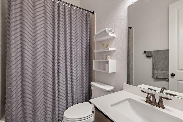 bathroom with curtained shower, toilet, vanity, and a textured wall