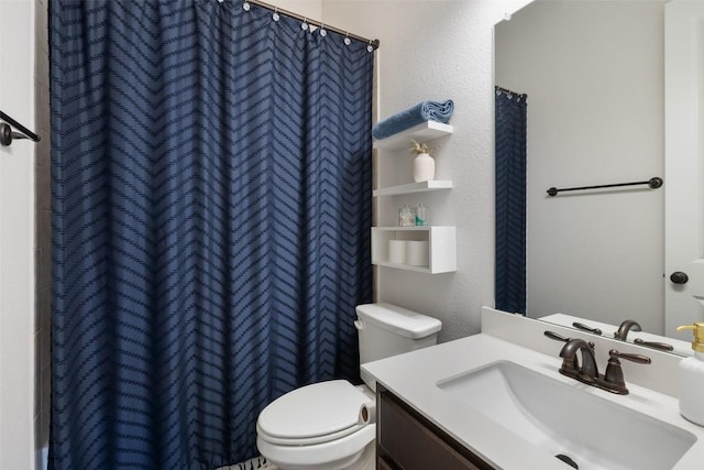 bathroom with vanity, curtained shower, toilet, and a textured wall