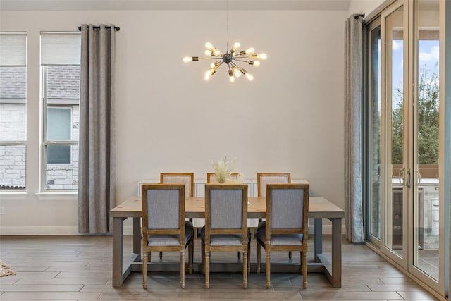 dining room with light wood-style flooring, baseboards, and a chandelier