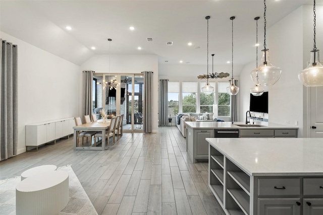 kitchen featuring wood finish floors, a sink, gray cabinetry, light countertops, and vaulted ceiling