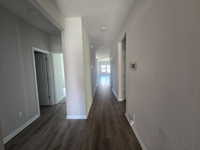 hallway with dark wood-type flooring and baseboards