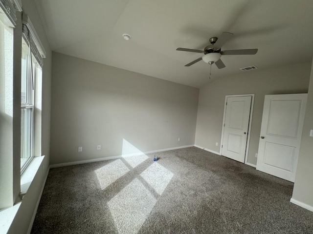 empty room featuring a ceiling fan, baseboards, visible vents, vaulted ceiling, and dark carpet