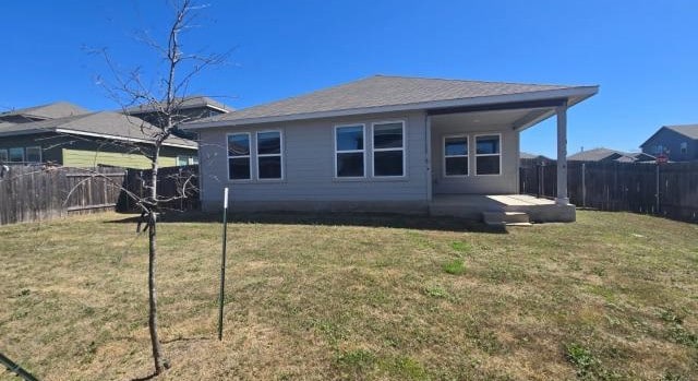 rear view of house with a patio area, a yard, and a fenced backyard