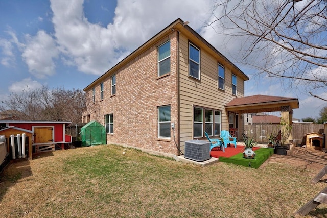 back of property with brick siding, a patio area, a yard, and fence