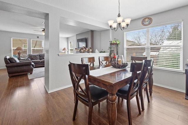 dining room with ceiling fan with notable chandelier, baseboards, and wood finished floors