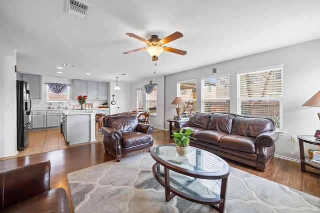 living area with visible vents, ceiling fan, baseboards, recessed lighting, and light wood-style floors