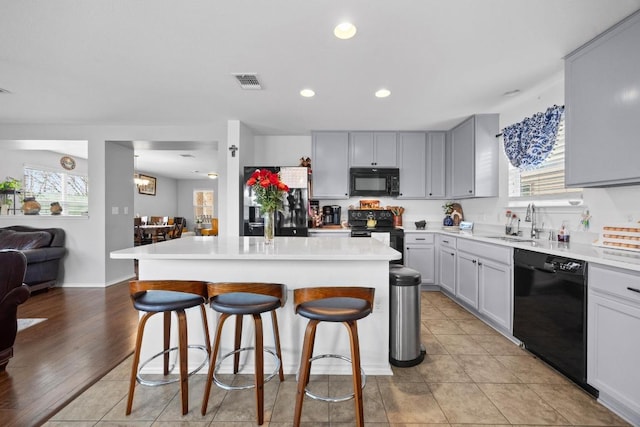 9017 Edmundsbury Dr, Austin, TX 78747 - kitchen featuring black appliances, a breakfast bar area, a kitchen island, recessed lighting, and light countertops