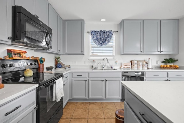 kitchen with black appliances, gray cabinets, a sink, light countertops, and light tile patterned floors